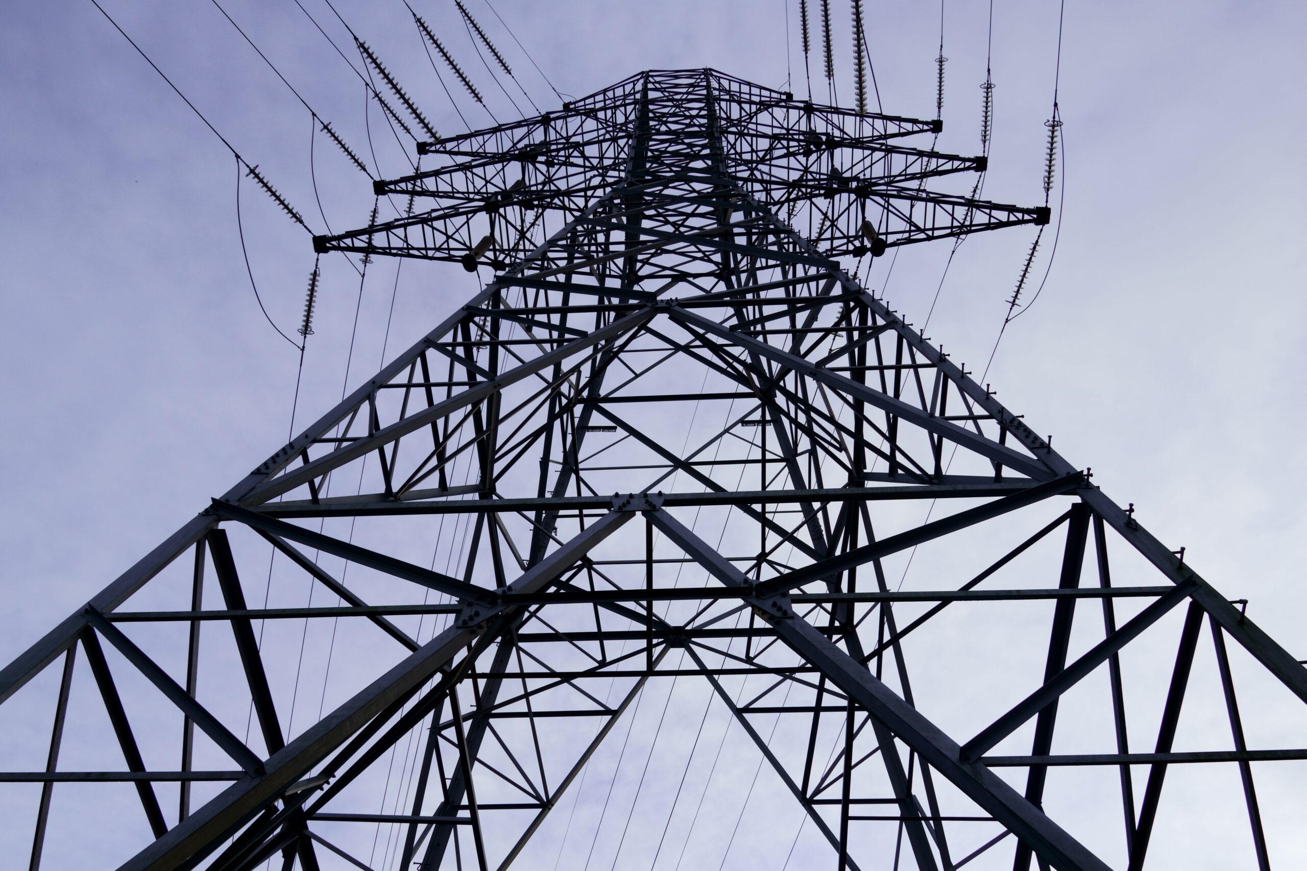 Dynamic perspective of a tall transmission tower against a clear blue sky, showcasing modern infrastructure.