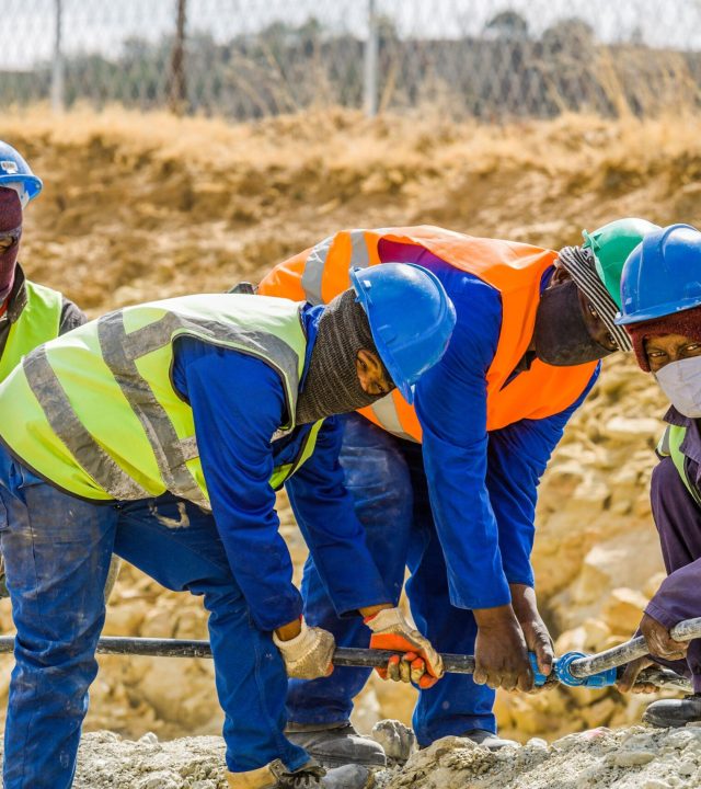 Team of construction workers in safety gear collaborating on a project outdoors in South Africa.