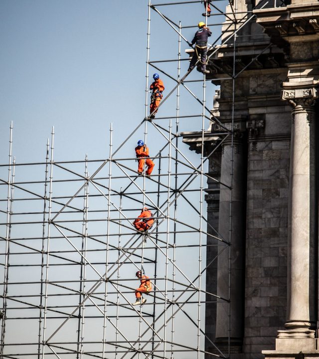 Workers on scaffolding near historic building in Mexico City. Urban construction setting.
